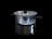 A shiny stainless steel pot with a glass lid is positioned against a black background. The pot has black handles on either side and a matching black knob on the lid. It is highly reflective, capturing light and mirrored reflections of its surroundings.