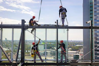 Team of installers carefully fitting a large window frame on a multi-story building.