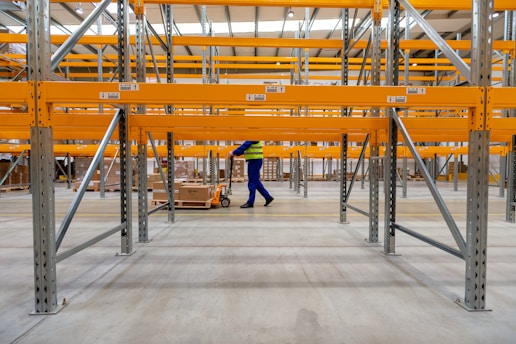 A warehouse worker using industrial cleaning equipment in a large commercial space.