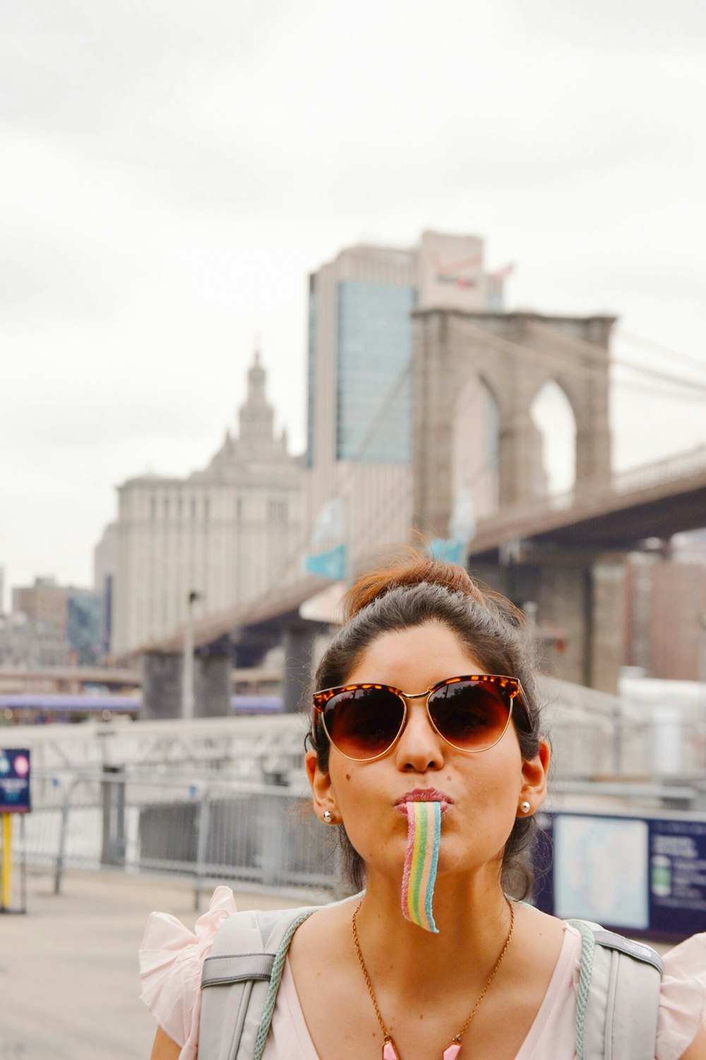 a woman wearing sunglasses and eating a rainbow lollipop