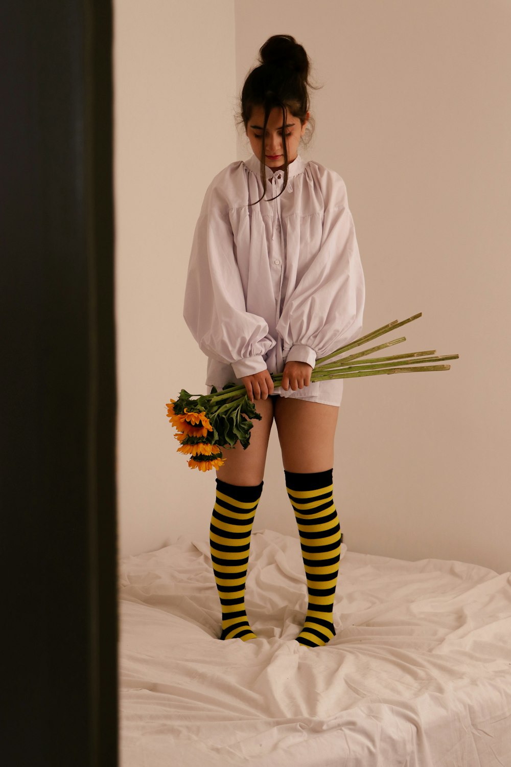 una donna in piedi sopra un letto che tiene un mazzo di fiori