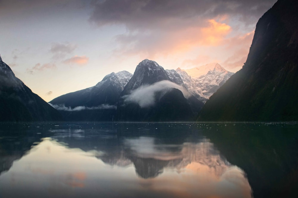 a body of water surrounded by mountains under a cloudy sky