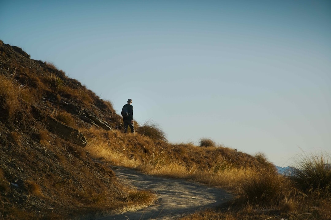 a man standing on top of a grass covered hillside,