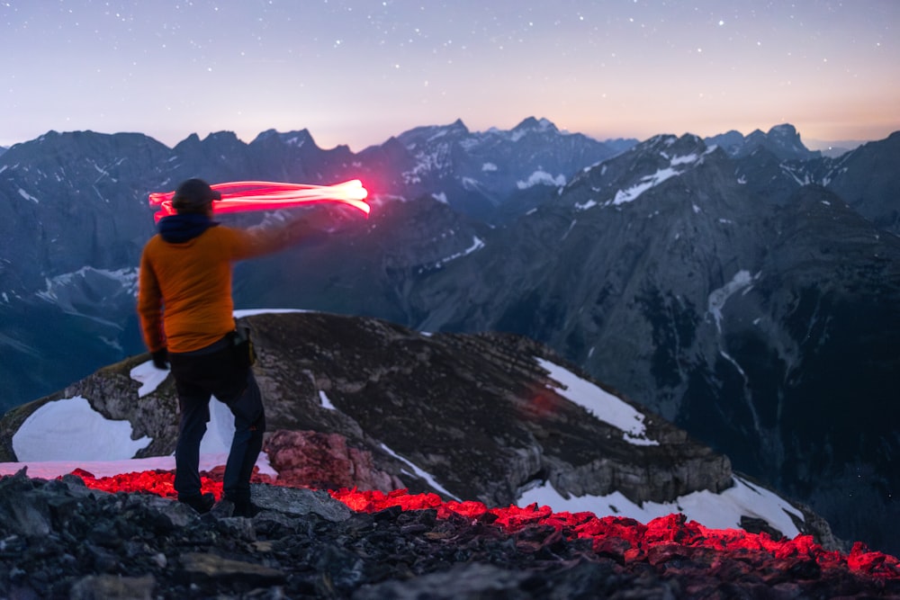 Un hombre parado en la cima de una montaña sosteniendo un sable de luz