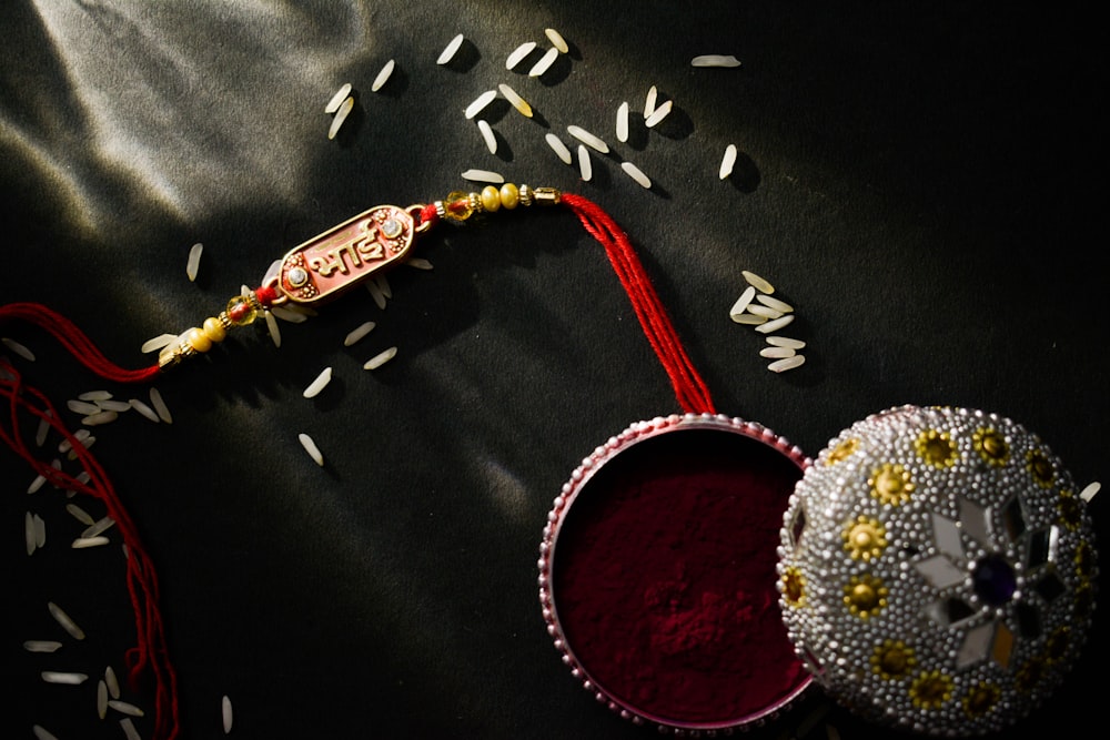 a red and white container with a red string and a red and gold beaded