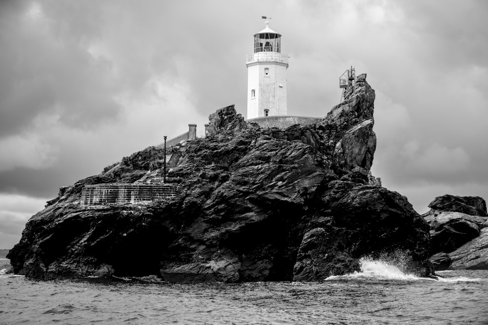 a black and white photo of a lighthouse on a rock
