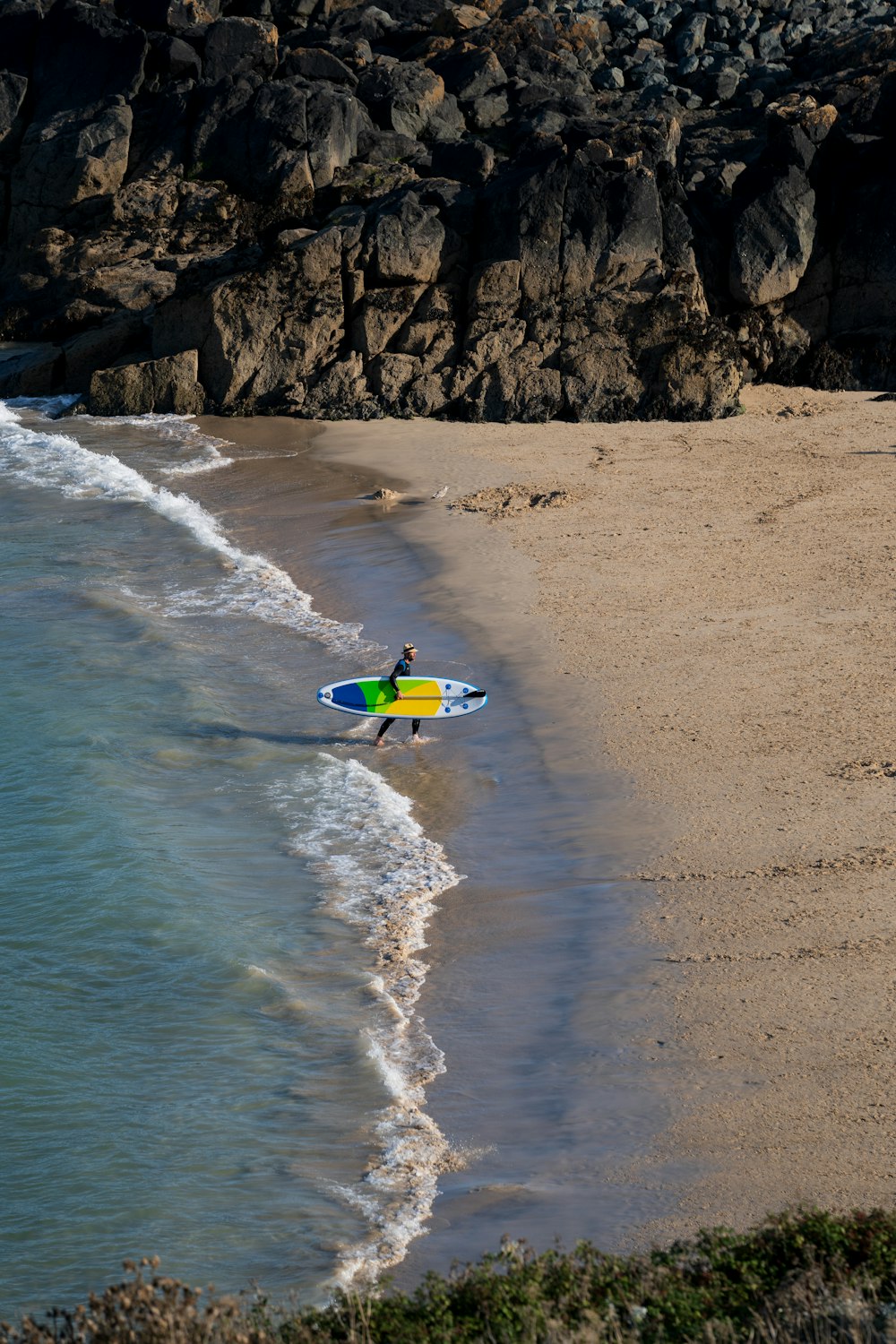 a man holding a surfboard on top of a sandy beach