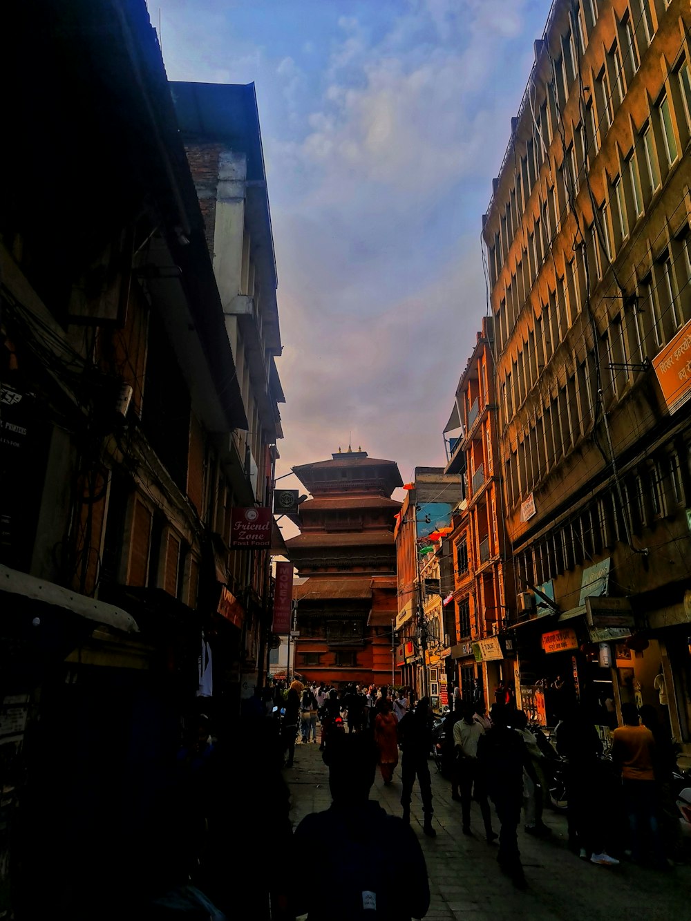 a group of people walking down a street next to tall buildings