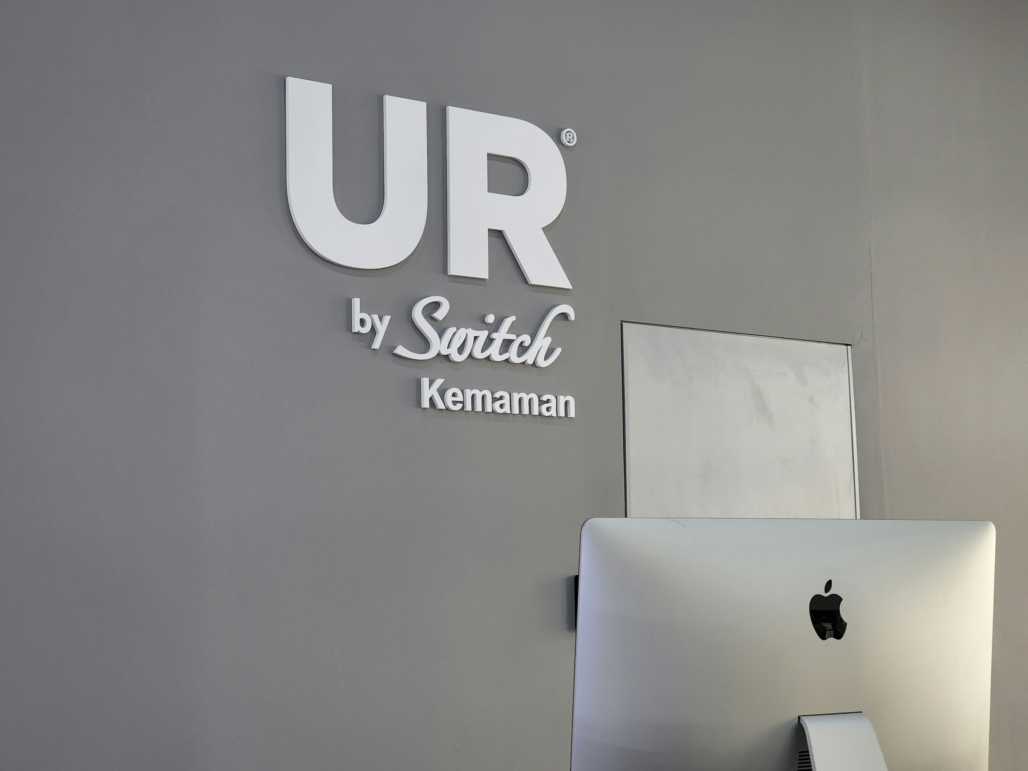 a computer on a desk in front of a sign