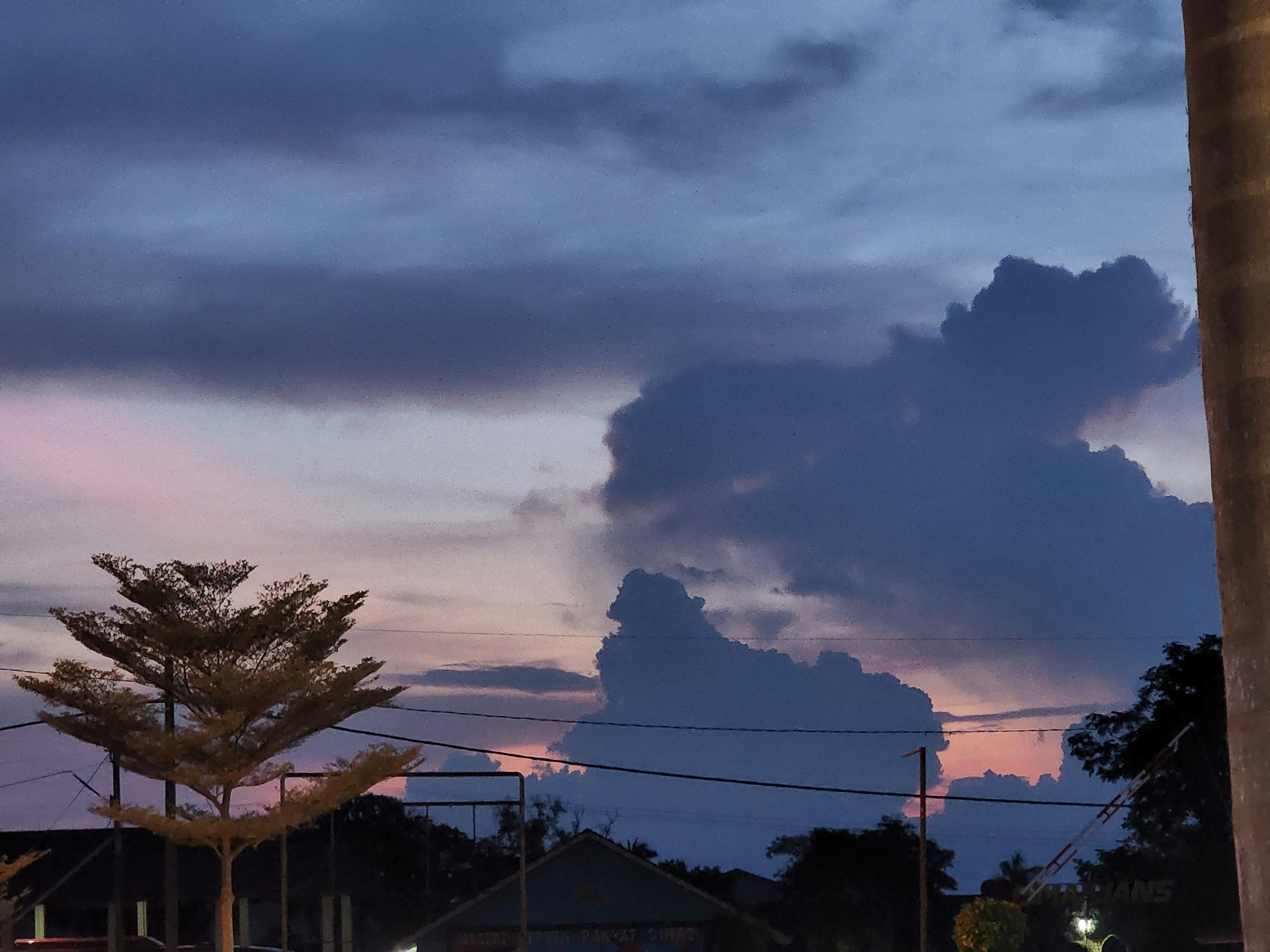 a large cloud looms in the sky over a neighborhood