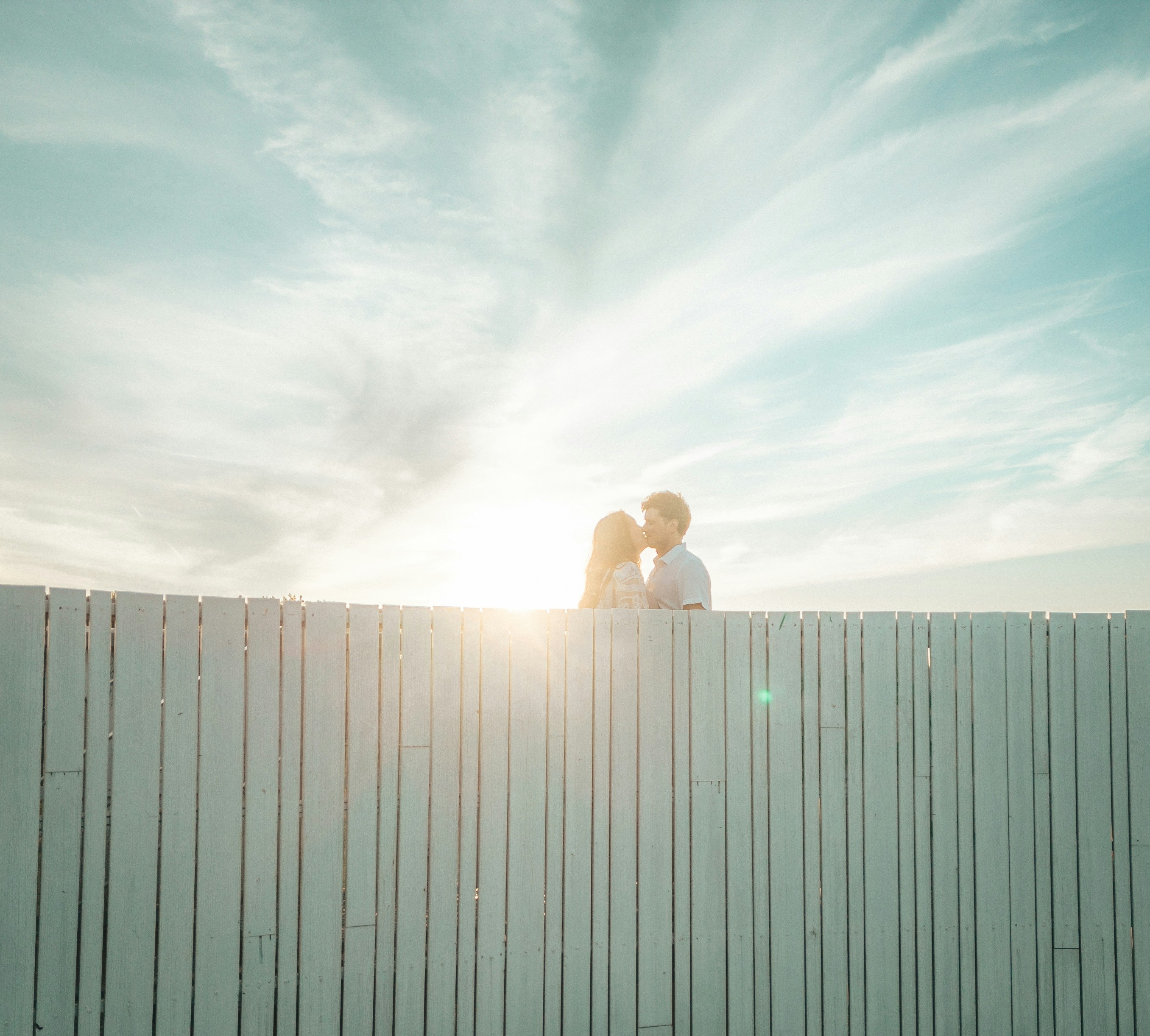 a man and a woman kissing on a fence