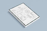 A stack of forms placed against a light blue background. Each form contains various sections including checkboxes, a circular diagram, tables, and lines for handwritten information. The forms also have a decorative border featuring green patterns.