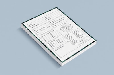 A stack of forms placed against a light blue background. Each form contains various sections including checkboxes, a circular diagram, tables, and lines for handwritten information. The forms also have a decorative border featuring green patterns.