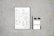 A document with checkboxes and text is placed on a flat, textured gray surface. Next to it, there is a black pencil, two black binder clips, and two small blank cards. The document appears to be some kind of form or template, featuring French text and various sections for input or selection.