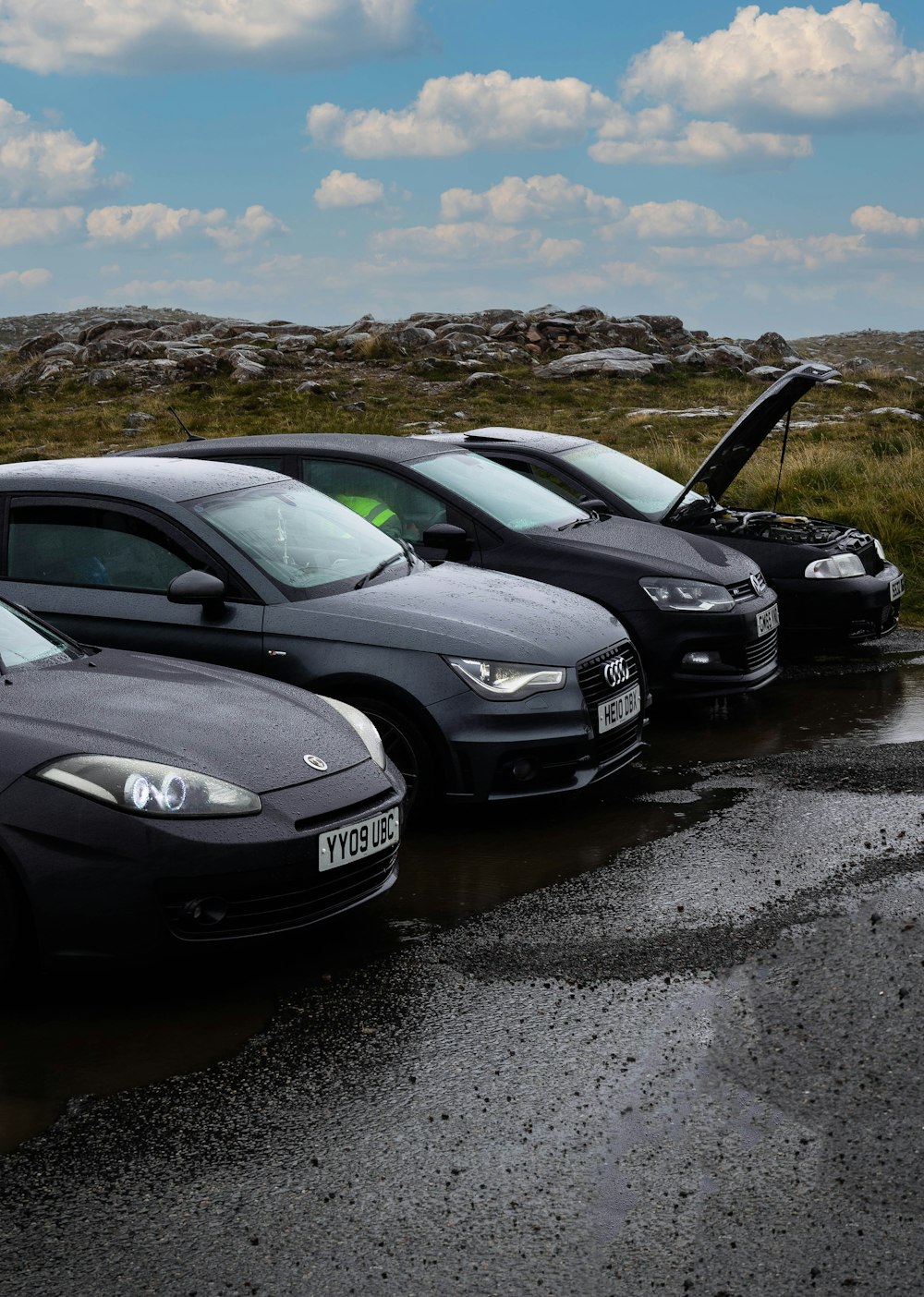 a row of parked cars sitting on top of a wet road