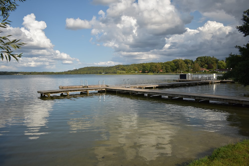 a dock on a lake with clouds in the sky