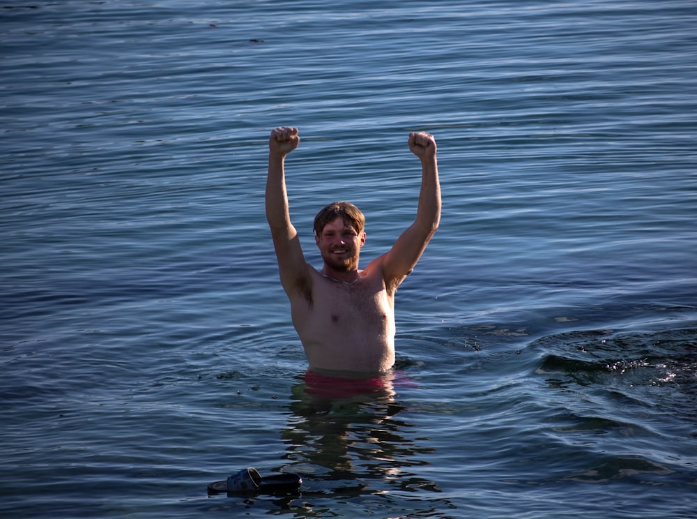 a man standing in a body of water with his arms in the air