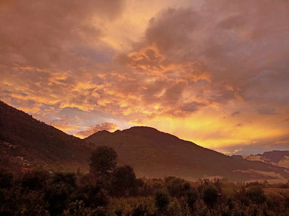 a sunset view of a mountain range with clouds in the sky