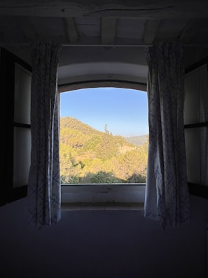 Bright and airy room with a large window overlooking lush green hills.