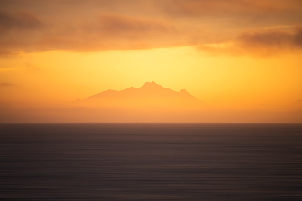 a large body of water with a mountain in the distance