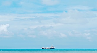 A serene blue-toned image of a modern ship navigating calm seas under a bright sky.