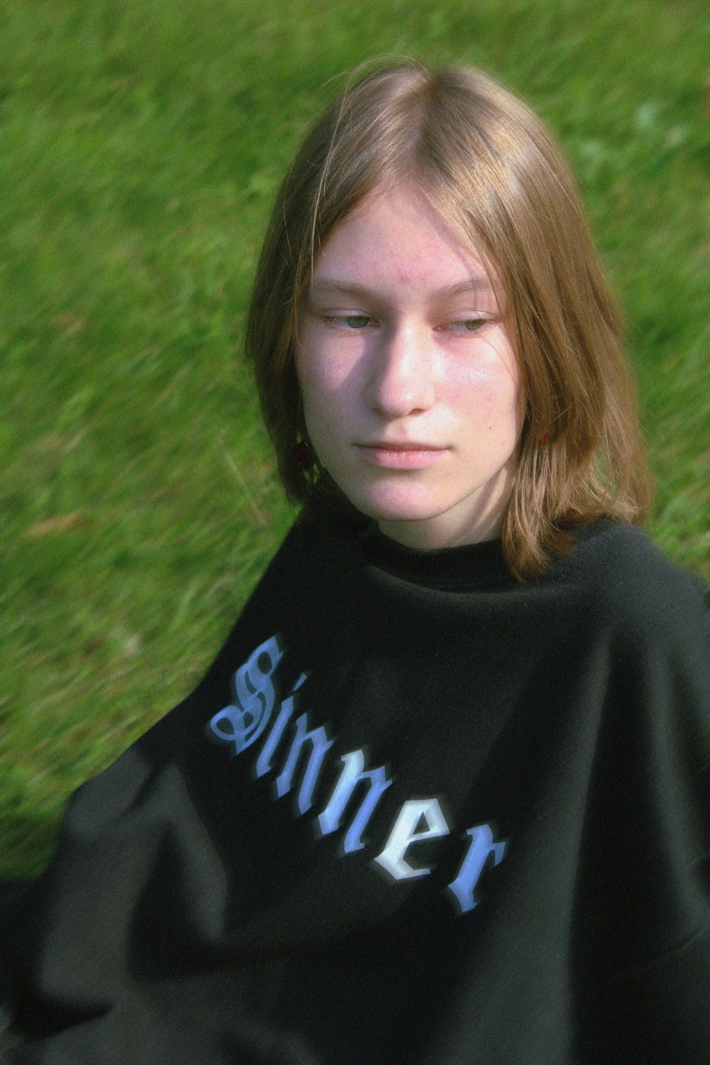 a young woman sitting in the grass with her eyes closed