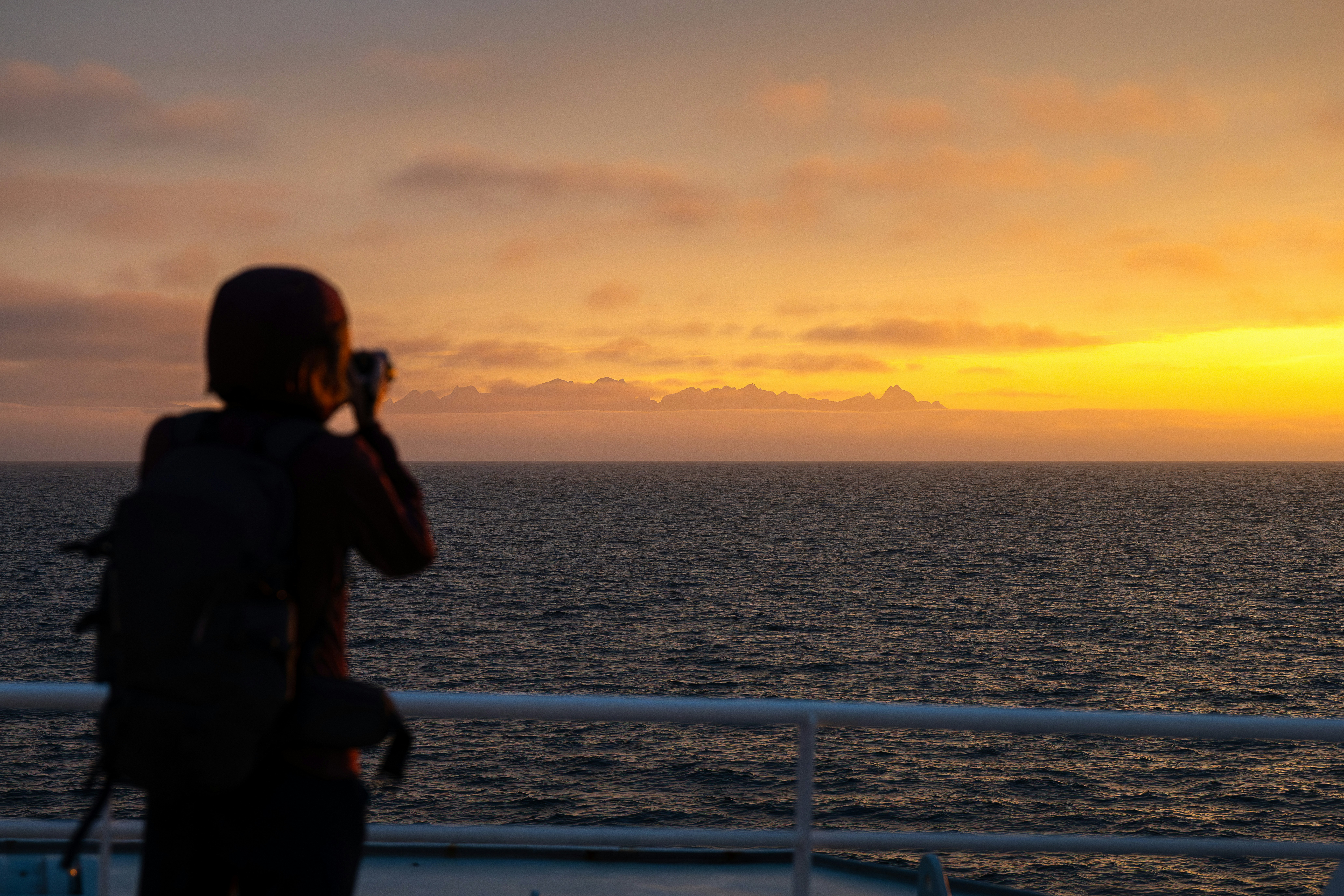 a person taking a picture of a sunset on a boat