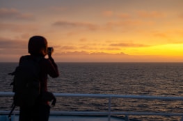 A scenic travel shot capturing a sunset with a person filming a vlog, embodying adventure and creativity.