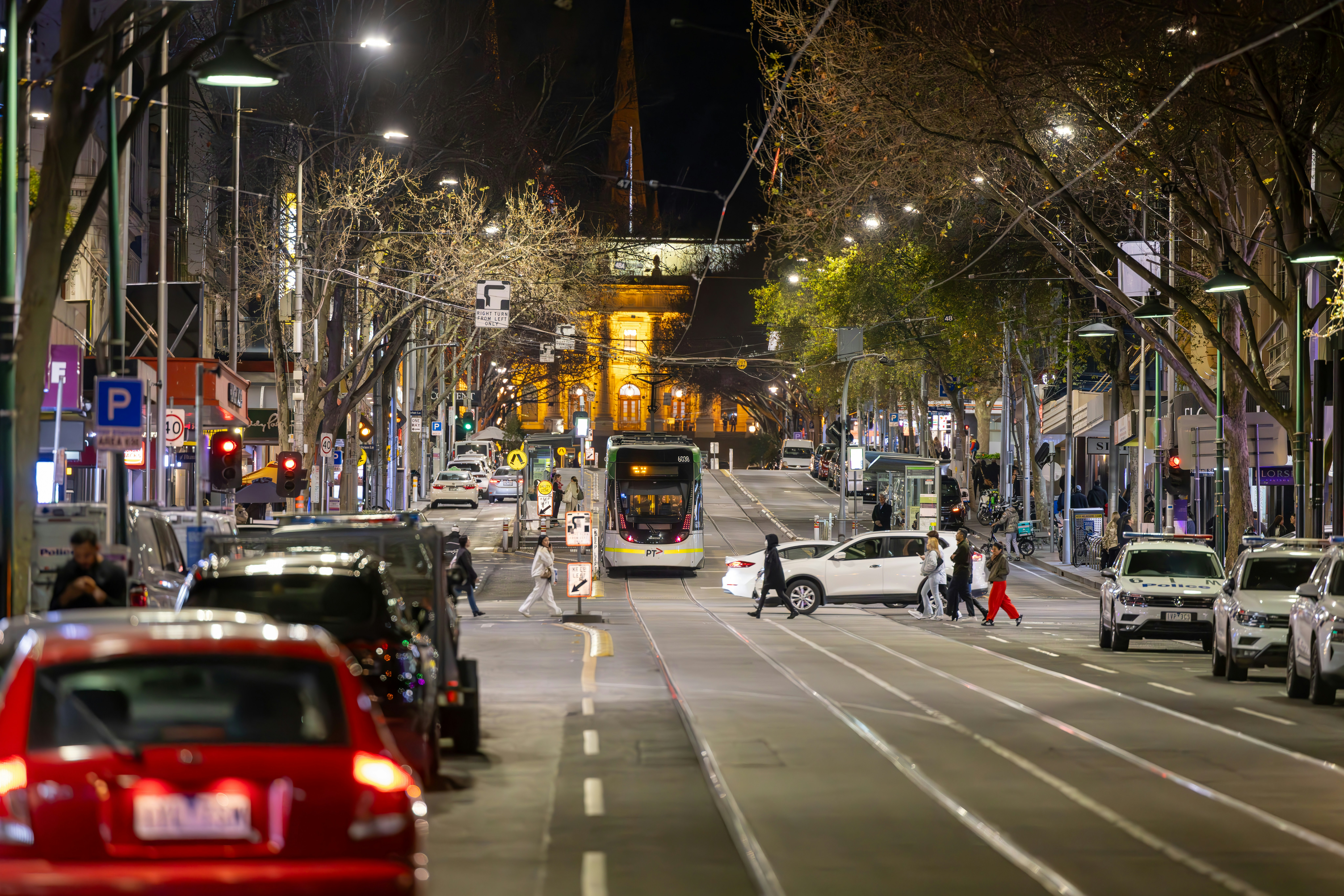 a busy city street at night with cars and people