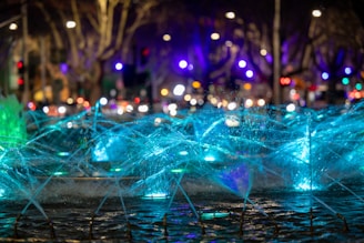 A close-up of a modern water fountain with dynamic water movement and colorful lighting at dusk.