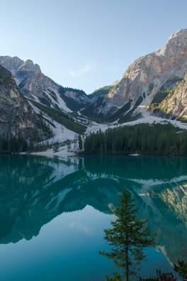 Drone capturing a crystal-clear lake nestled among forested mountains.