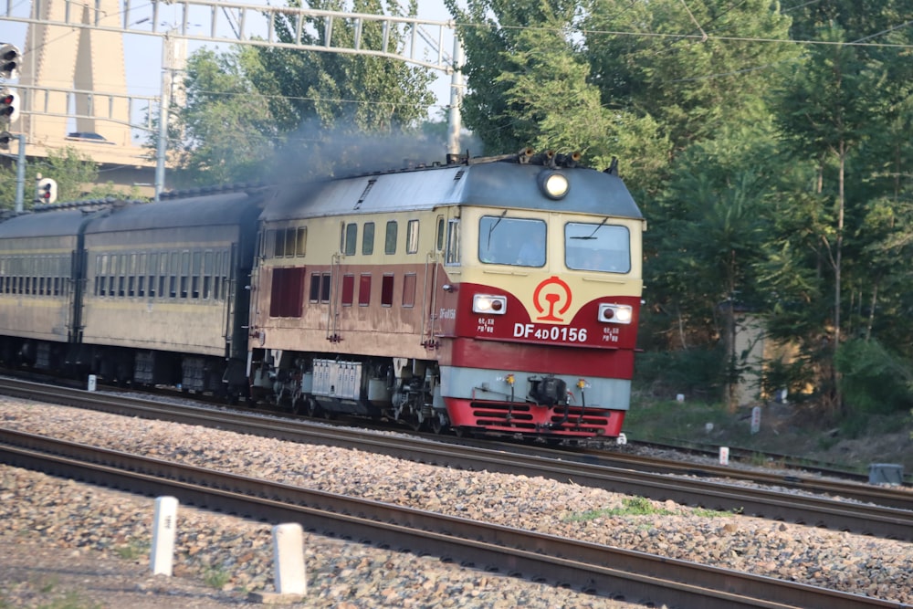 Ein Zug, der neben einem Wald die Bahngleise hinunterfährt