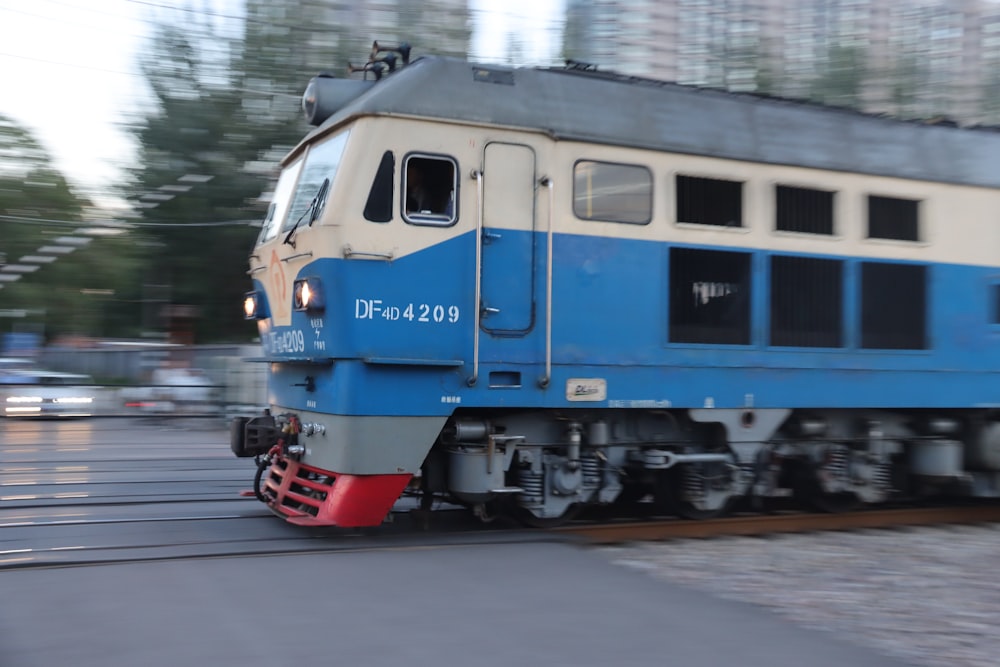 a blue and white train traveling down train tracks