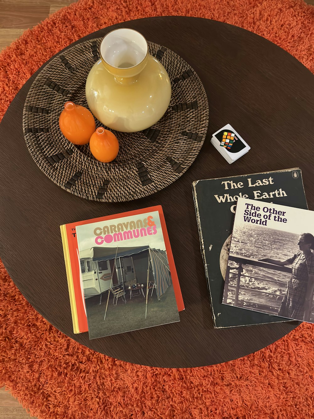 a table topped with books and a vase filled with oranges