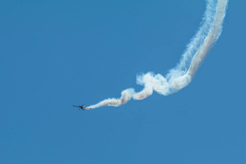 Un aereo vola nel cielo lasciando una scia di fumo