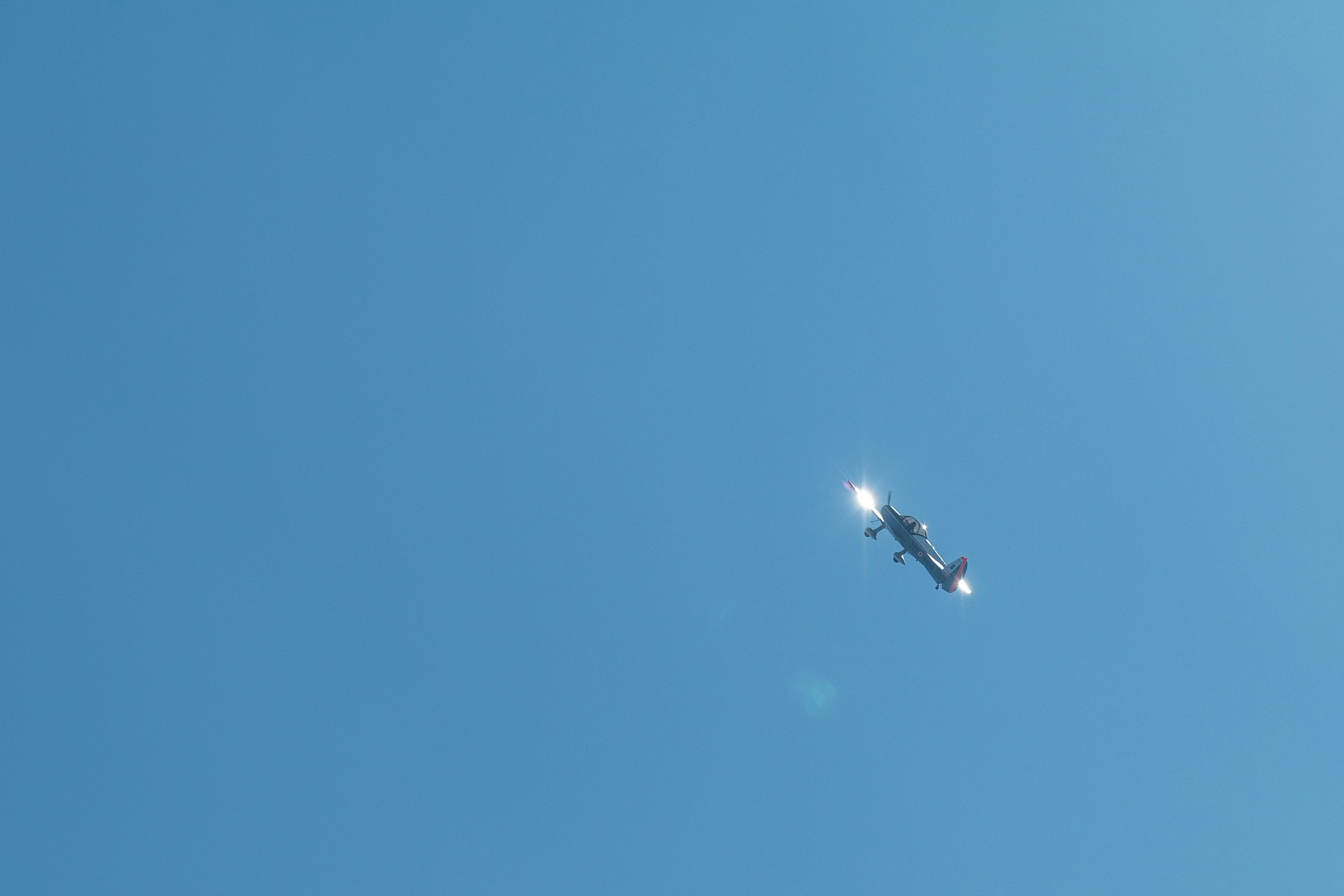 An aerial view of a dense, forested hilly terrain, indicative of Karbi Anglong, with a faint smoke plume in the distance.