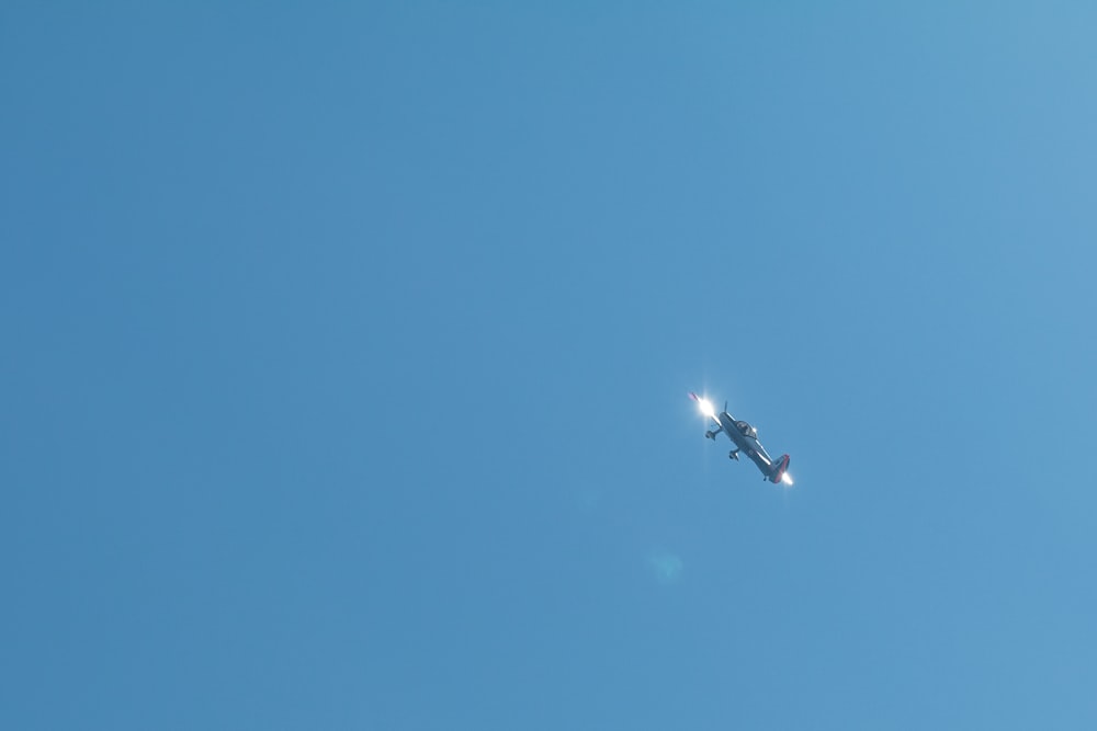 a small airplane flying through a blue sky