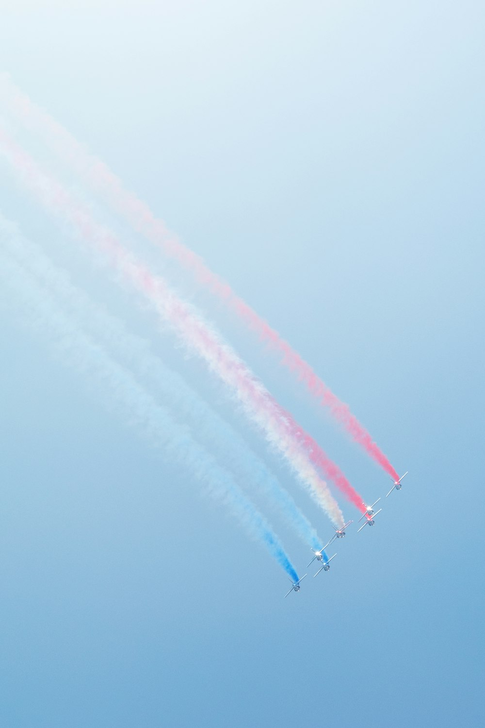 a group of jets flying through a blue sky