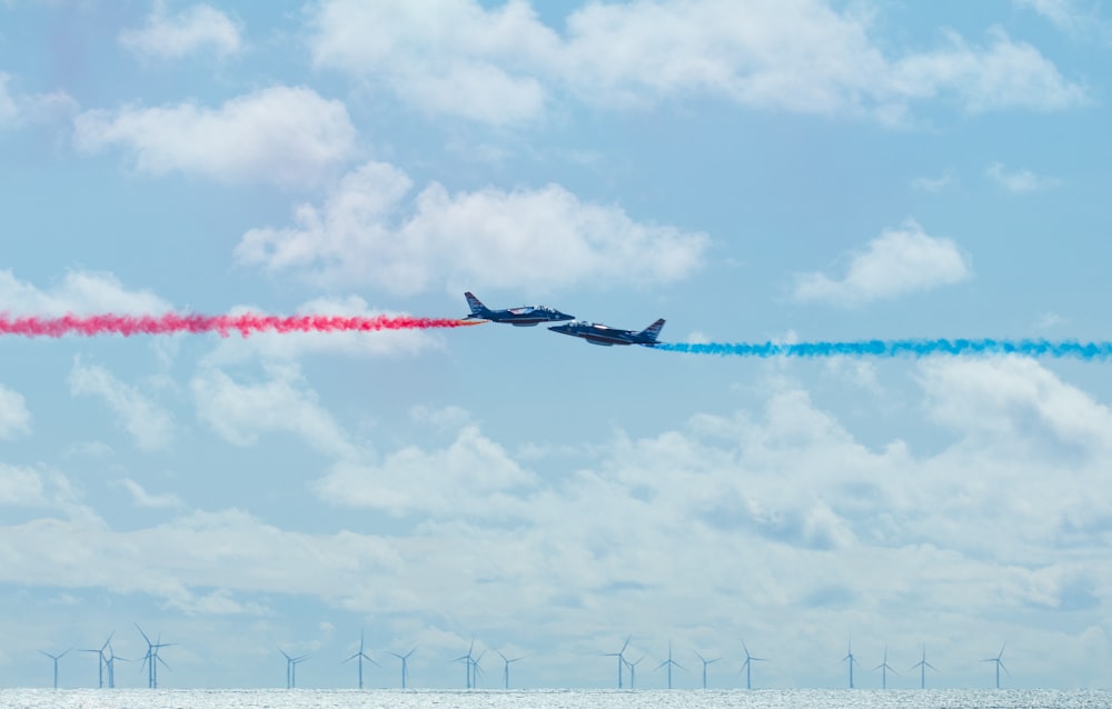 Due aeroplani che volano nel cielo con fumo colorato che esce da loro