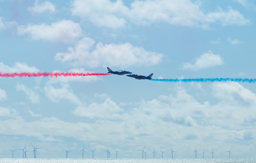 two airplanes flying in the sky with colored smoke coming out of them,