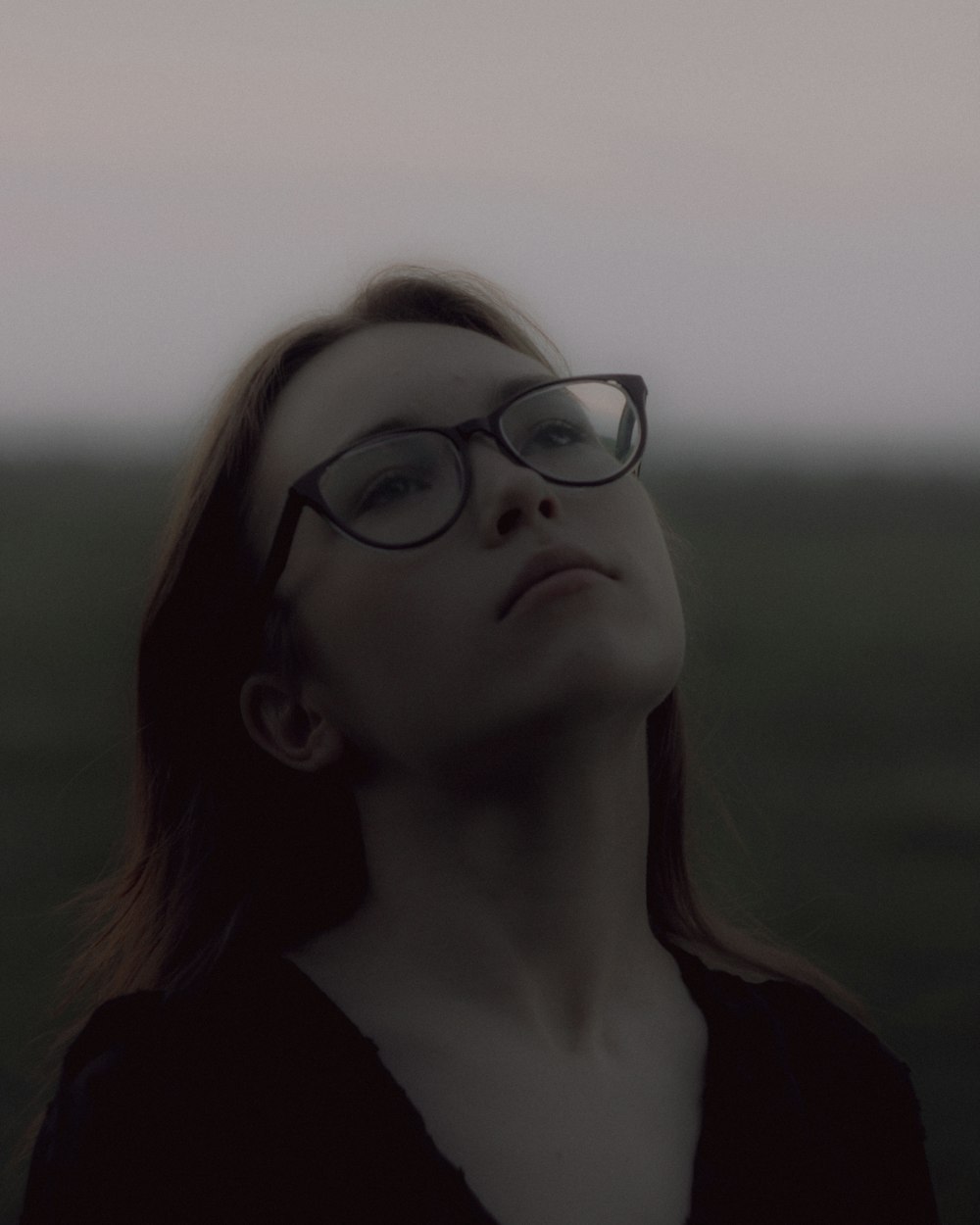a woman wearing glasses looking up into the sky