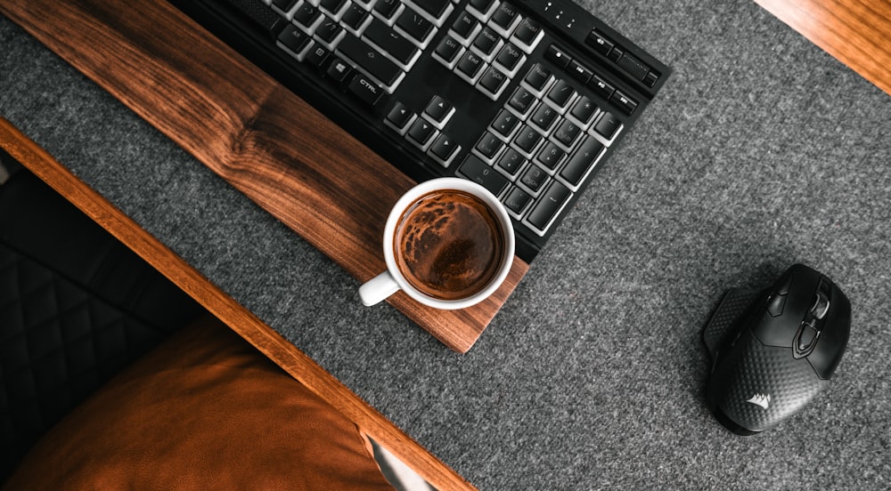 a cup of coffee next to a computer keyboard
