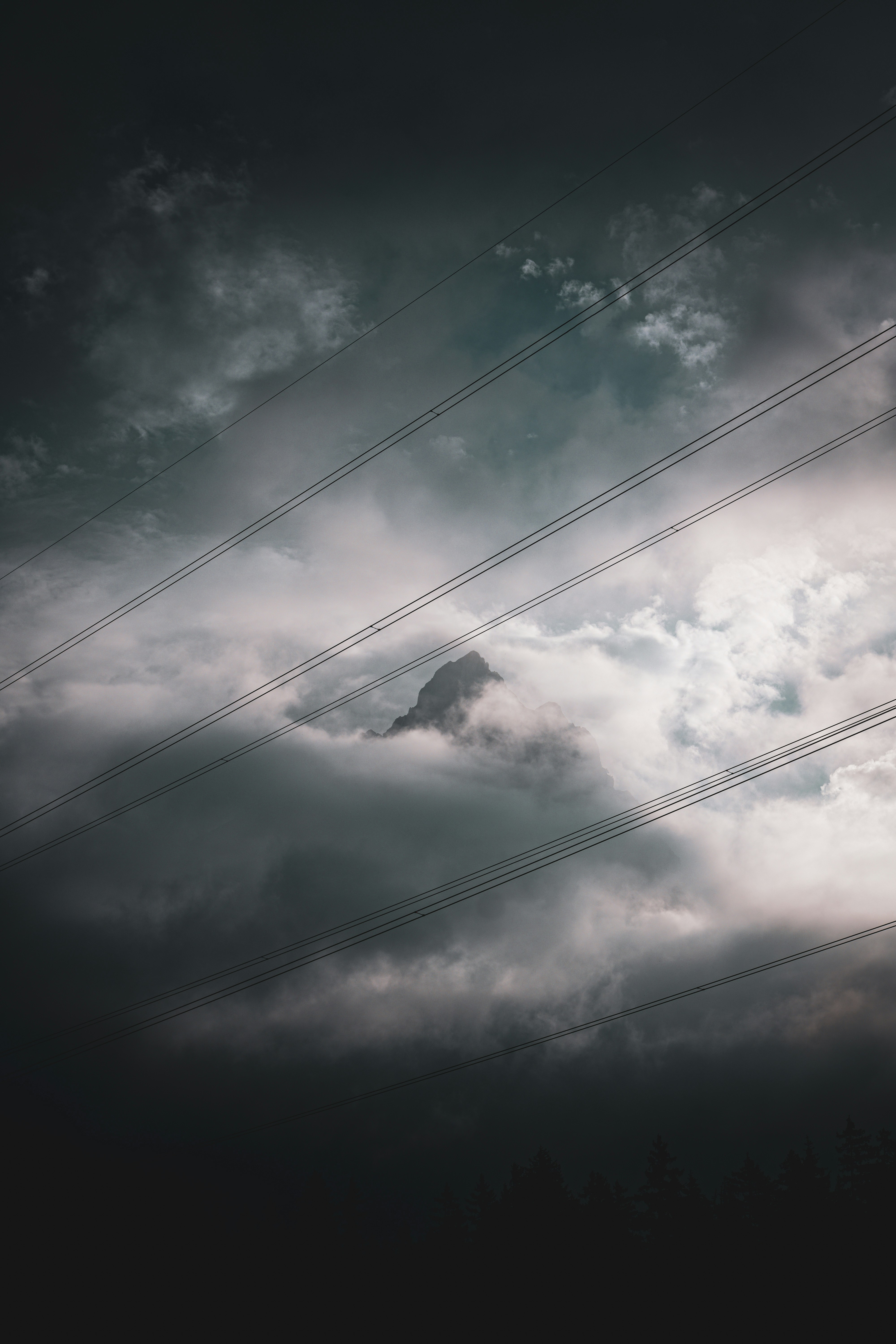 A cloudy sky with power lines and a mountain in the distance photo ...