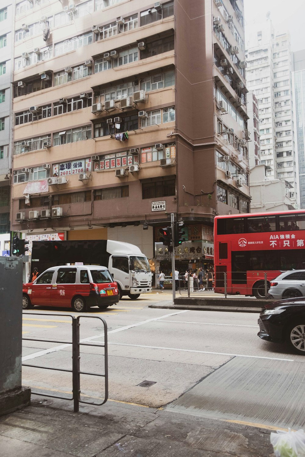 a red double decker bus driving past a tall building