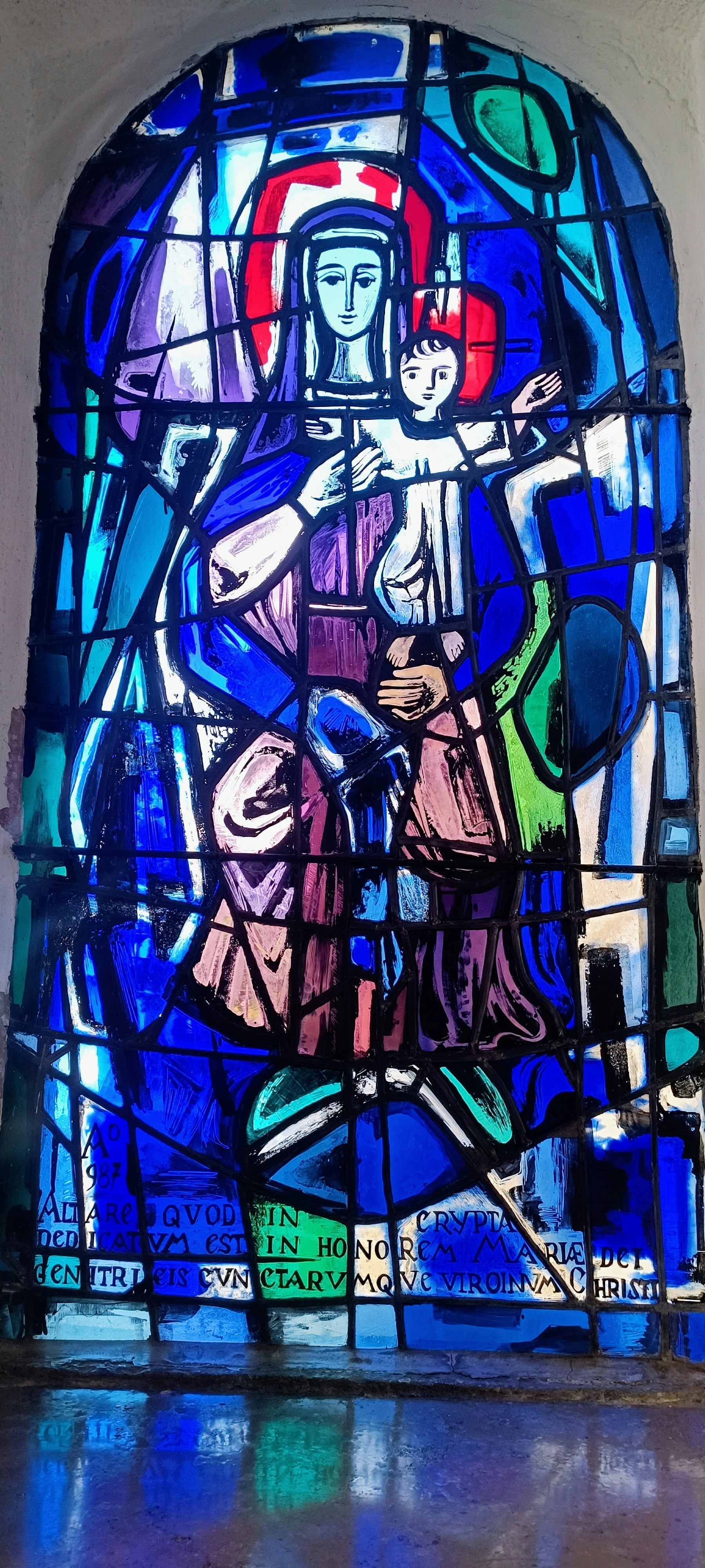 Stained glass window of the Virgin Mary in a Catholic cathedral, blue and gold tones, reverent light