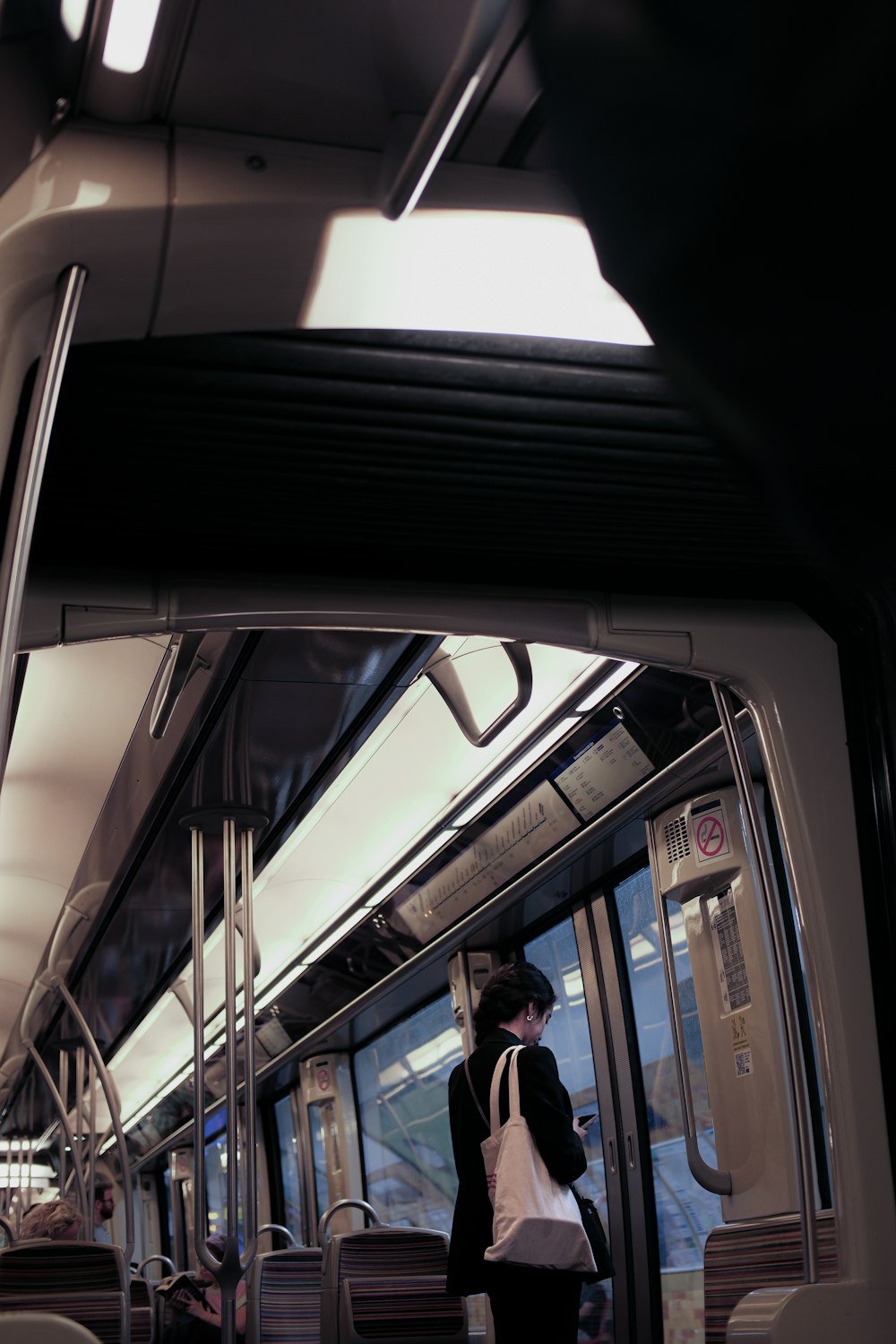 a woman is standing on a train looking at her cell phone