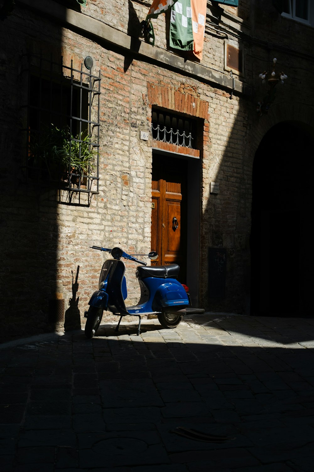 a blue scooter parked in front of a brick building