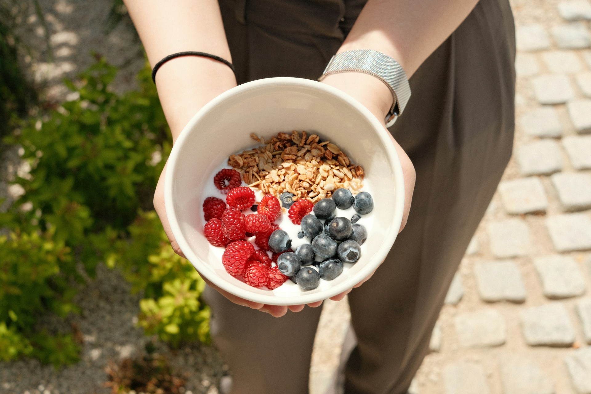 a person holding a bowl of cereal and berries