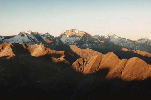 A panoramic mountain landscape showcasing dramatic peaks and golden sunlight.