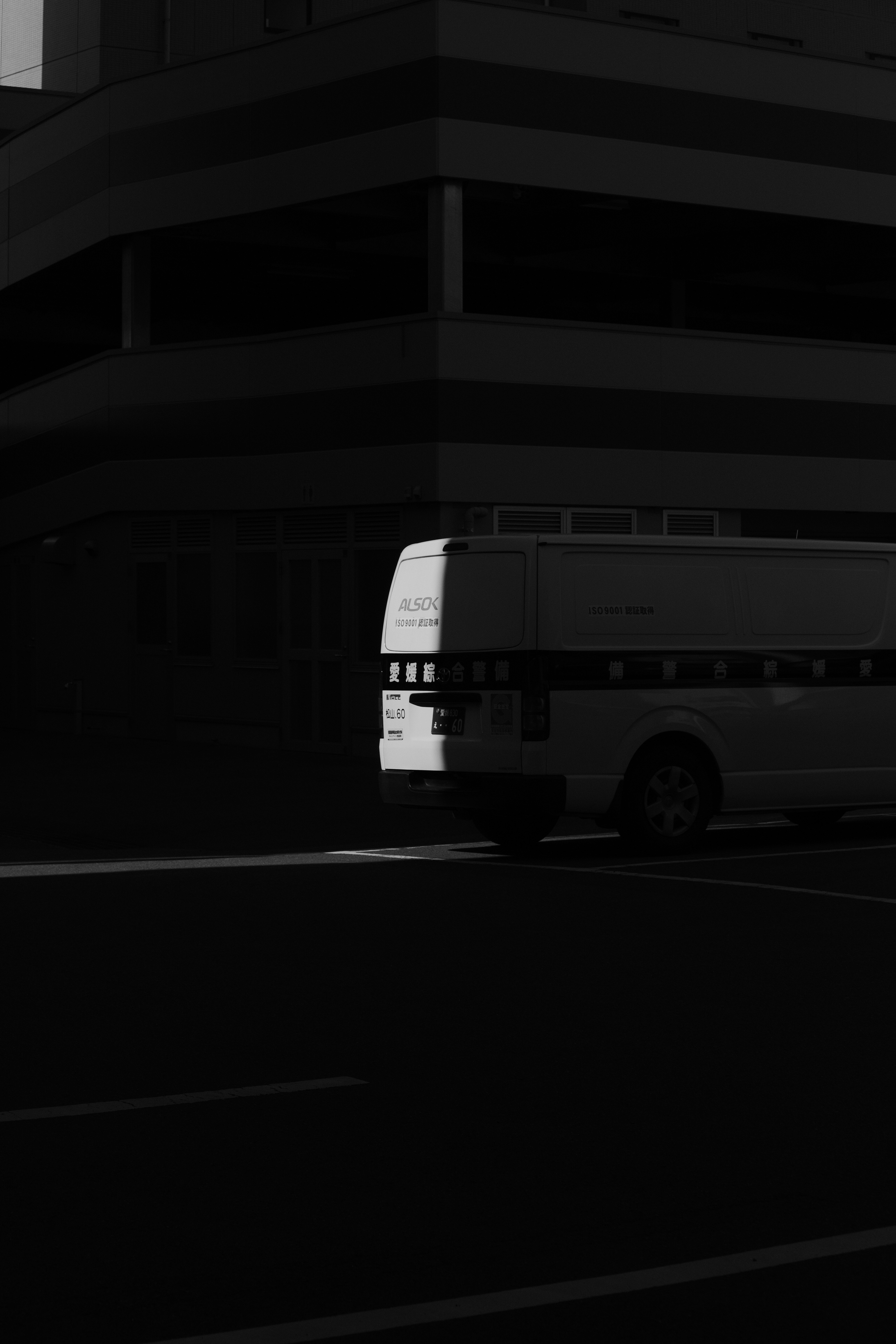 a black and white photo of a bus parked in front of a building